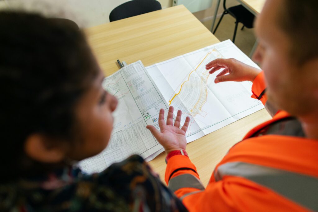 pexels-photo-3862384-3862384 Two engineers reviewing construction blueprints on a table in an office setting.